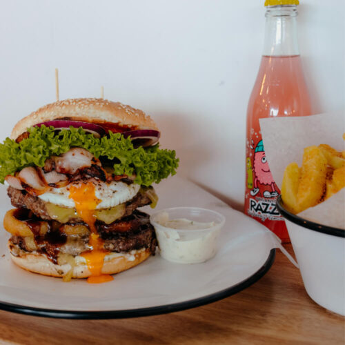 Picture of burger on plate with fries and a fizzy drink