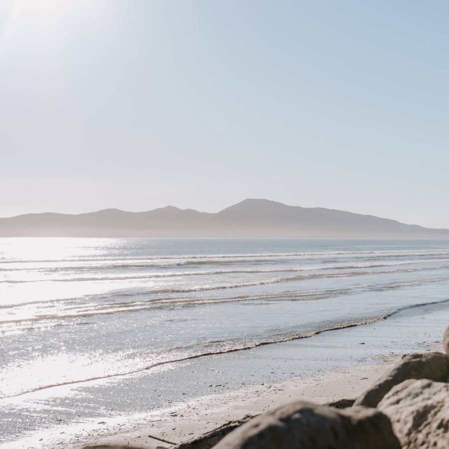 Picture of beach taken from rocks with mountains in the background