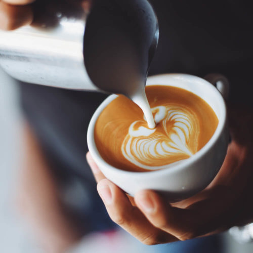 Picture of barista pouring milk into a coffee from milk jug