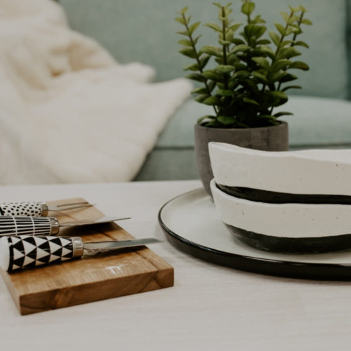 Picture of a table setting with cheese knifes, bowls and a potted plant