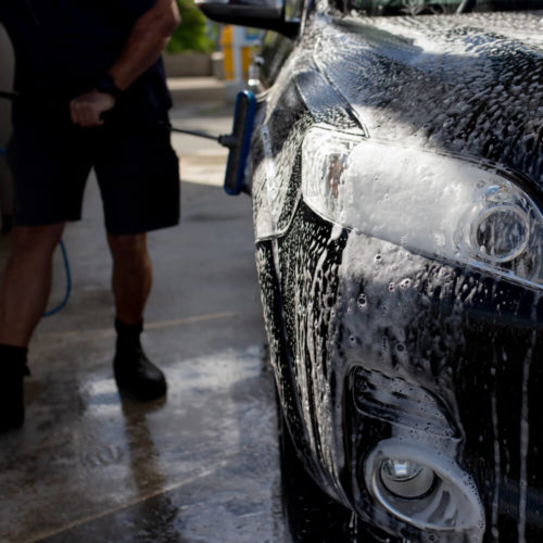 Picture of a man washing a car with a brush