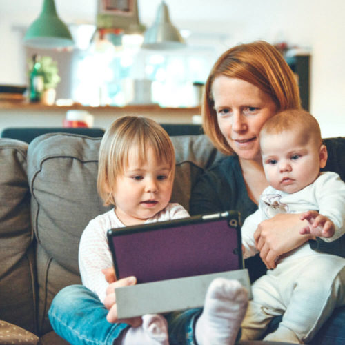 Picture of mum with two children on couch with device