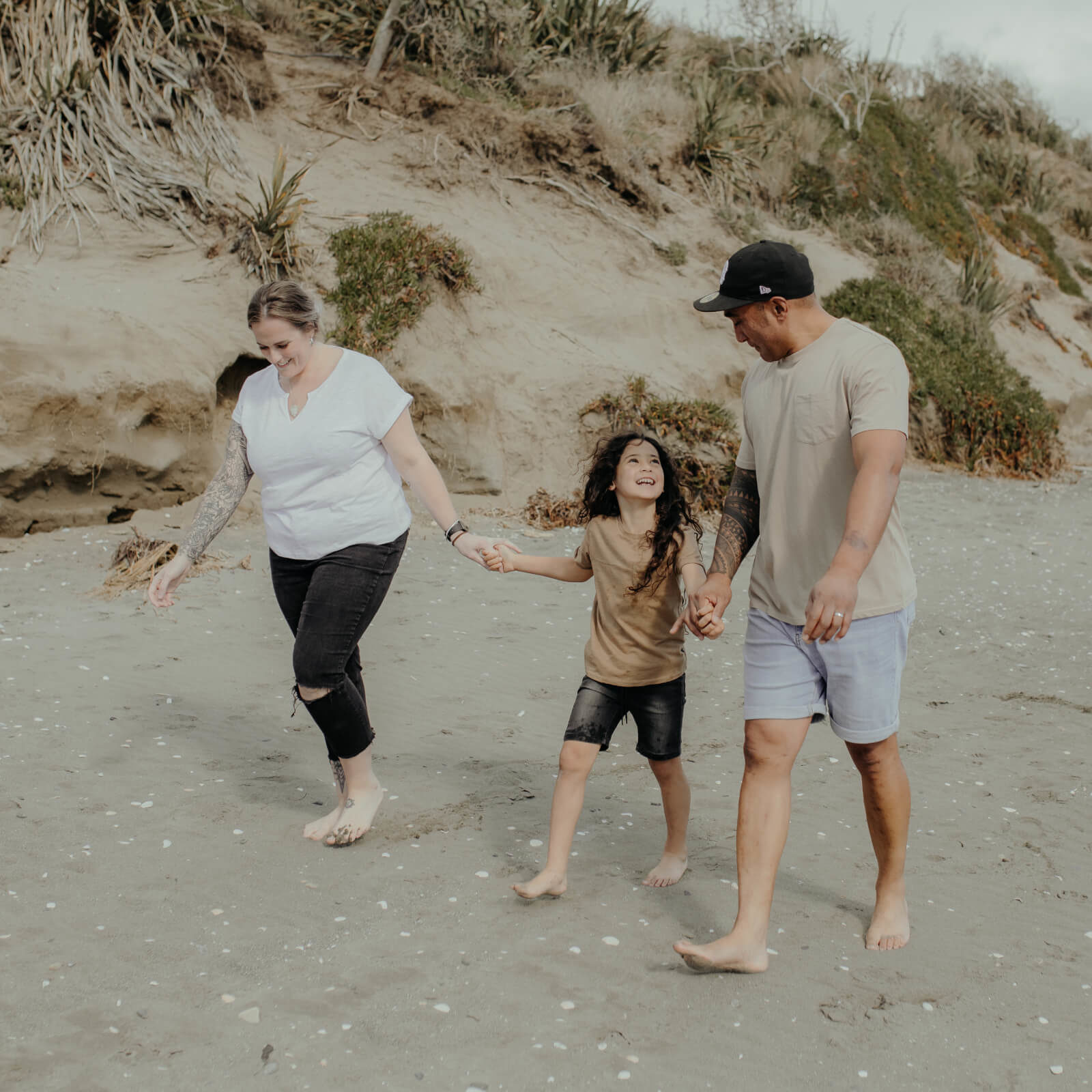 Picture of two parents holding hands with young girl on beach